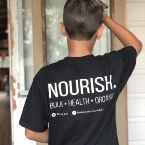 Boy facing door wearing nourish bulk, health, organics t-shirtt